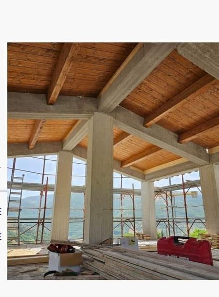 Interno di un edificio in costruzione: pilastri in cemento armato e copertura in legno